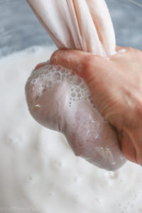 Squeezing Organic Homemade Almond Milk from nut milk bag